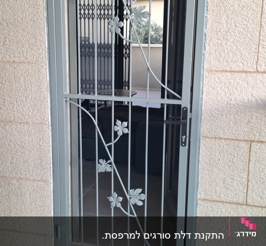 סורג ישר ממתכת נפתח עם עיטורי פרחים ועלים בחלון